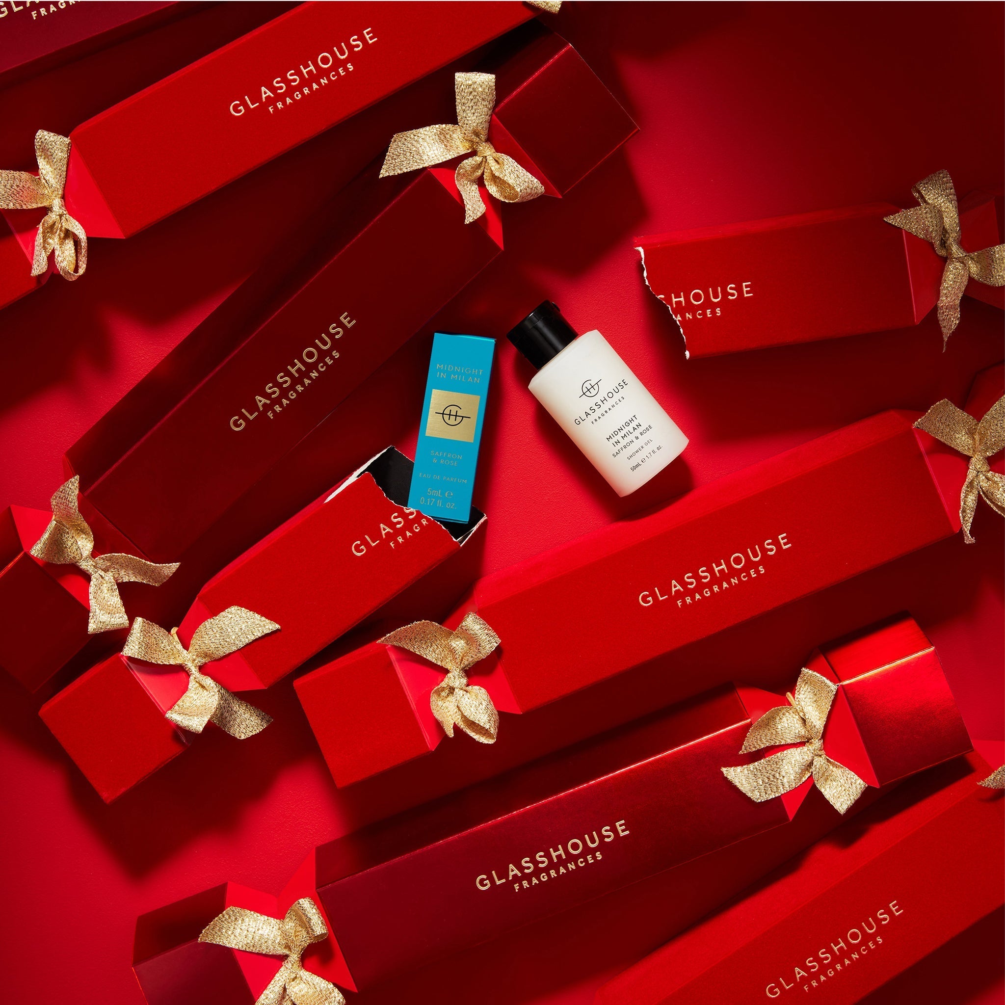 Multiple bon bons on red tabletop, one open revealing Glasshouse Fragrances Midnight in Milan Body Lotion and Eau de Parfum